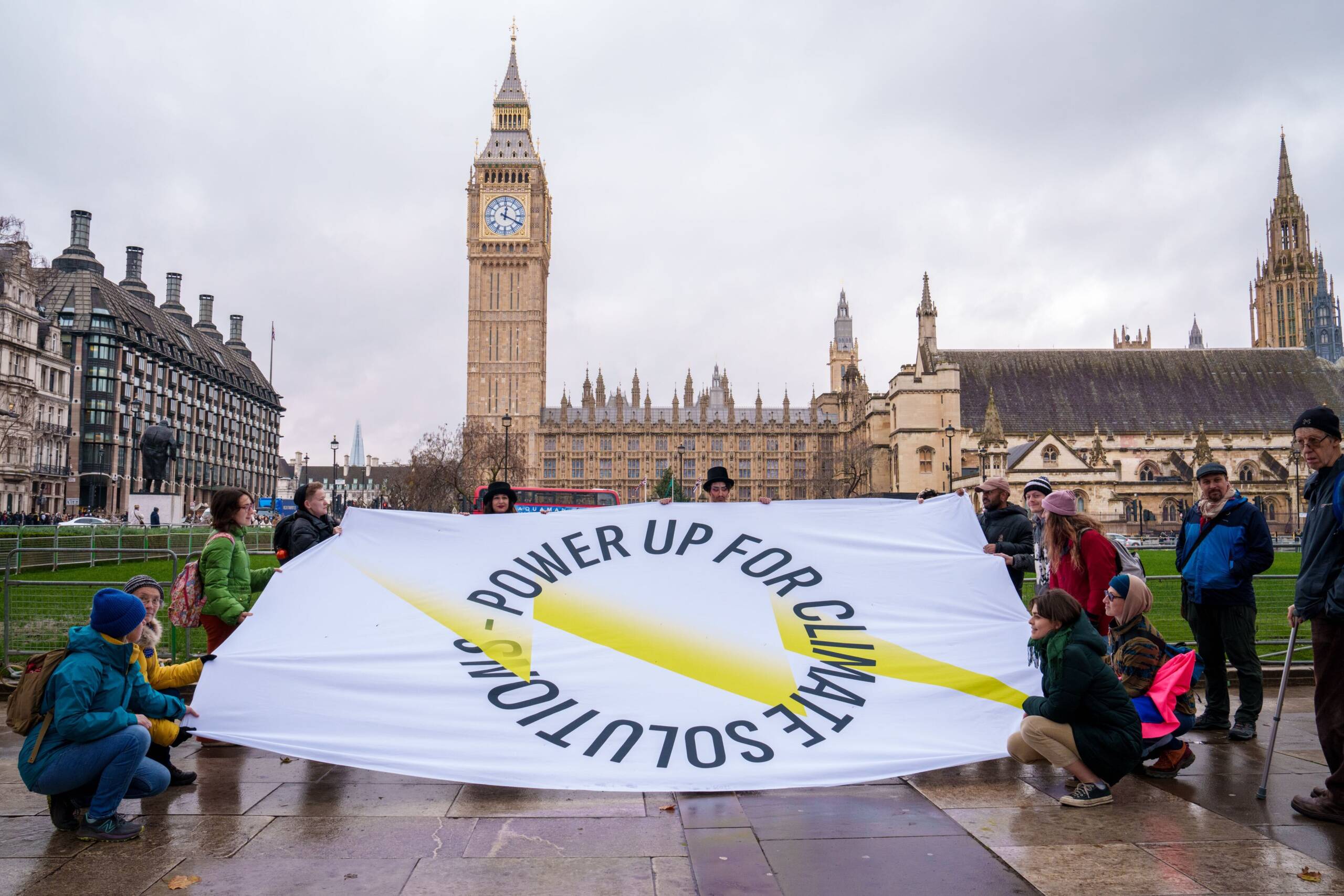 London, Inggris, 5 Desember: para aktivis membawa spanduk Power Up ke tempat-tempat ikonis di London guna meningkatkan kesadaran terhadap berbagai tuntutan kita – Perusahaan-perusahaan energi kotor harus membayar untuk kerusakan lingkungan dan perekonomian yang mereka sebabkan, serta untuk transisi adil menuju energi terbarukan. Kredit foto: James Klug